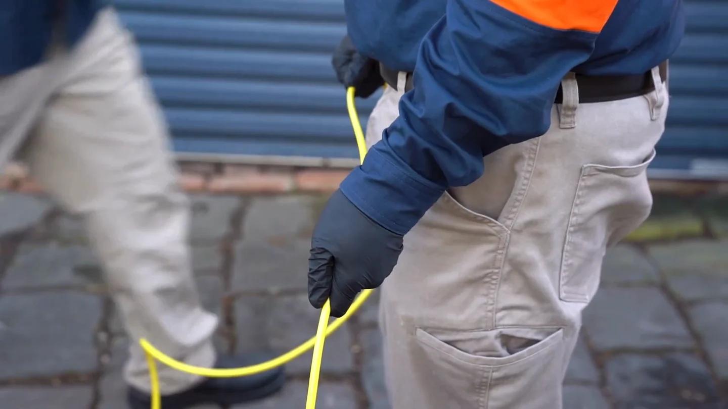 A sewer deployment: the Ferret lowered through a manhole, driving the pipe, and the crew at the base station